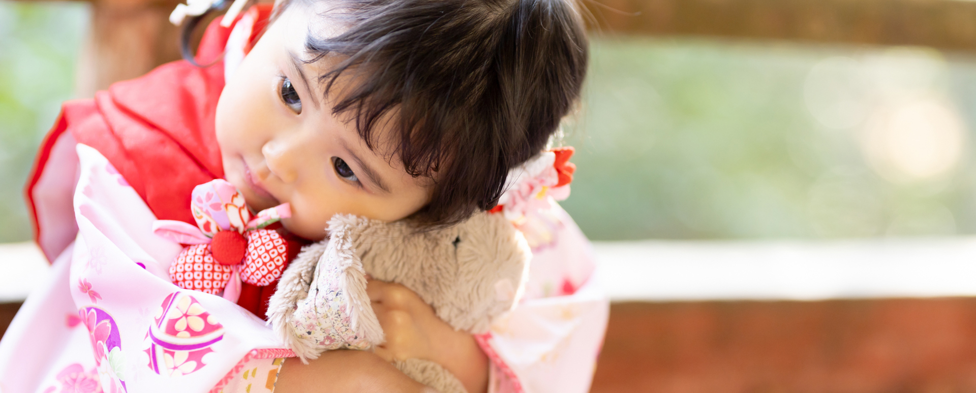 大分県大分市・柞原八幡宮での七五三。ピンクの着物を着た3歳の女の子が、大好きなぬいぐるみをぎゅっと抱きしめる姿。