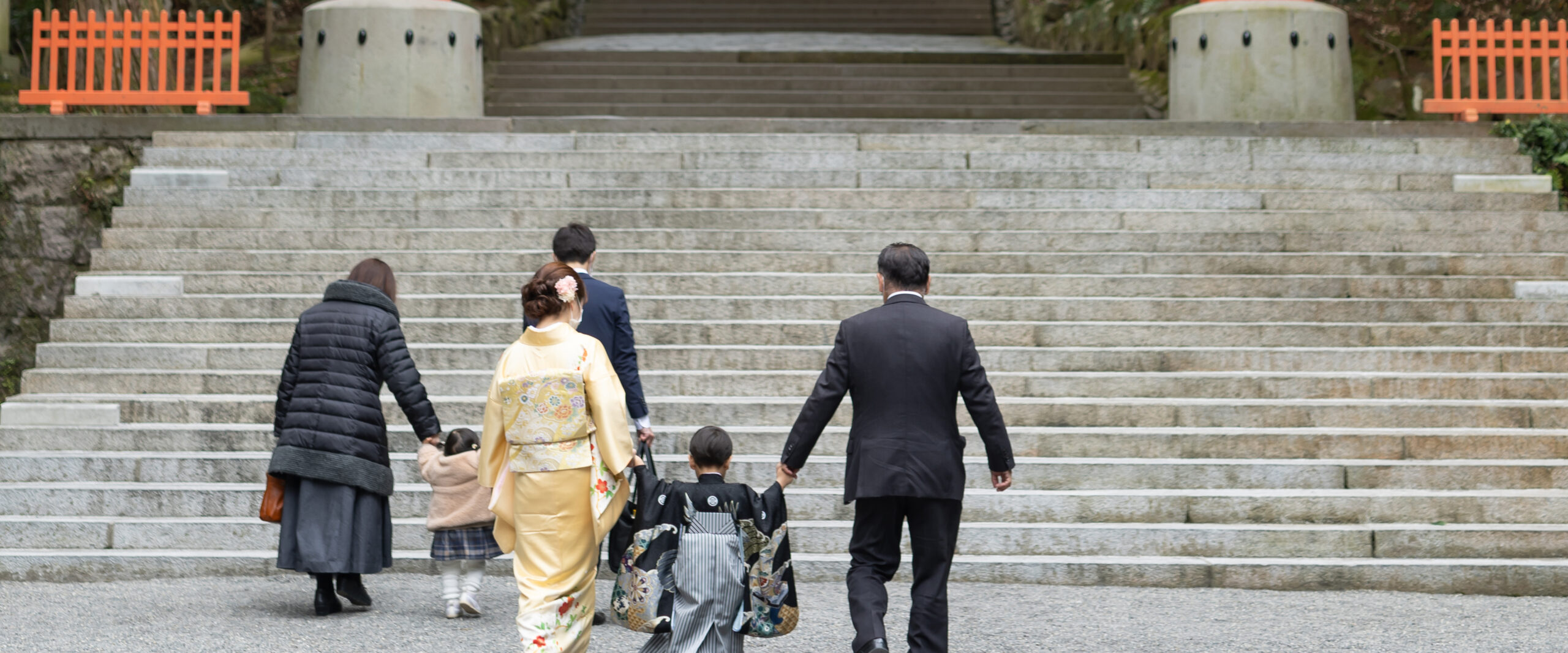 宇佐の宇佐神宮にある大きな石段を、着物姿のお母様やお子さまたちを囲んでご家族みんなで一段ずつ登っていくお参り当日の後ろ姿