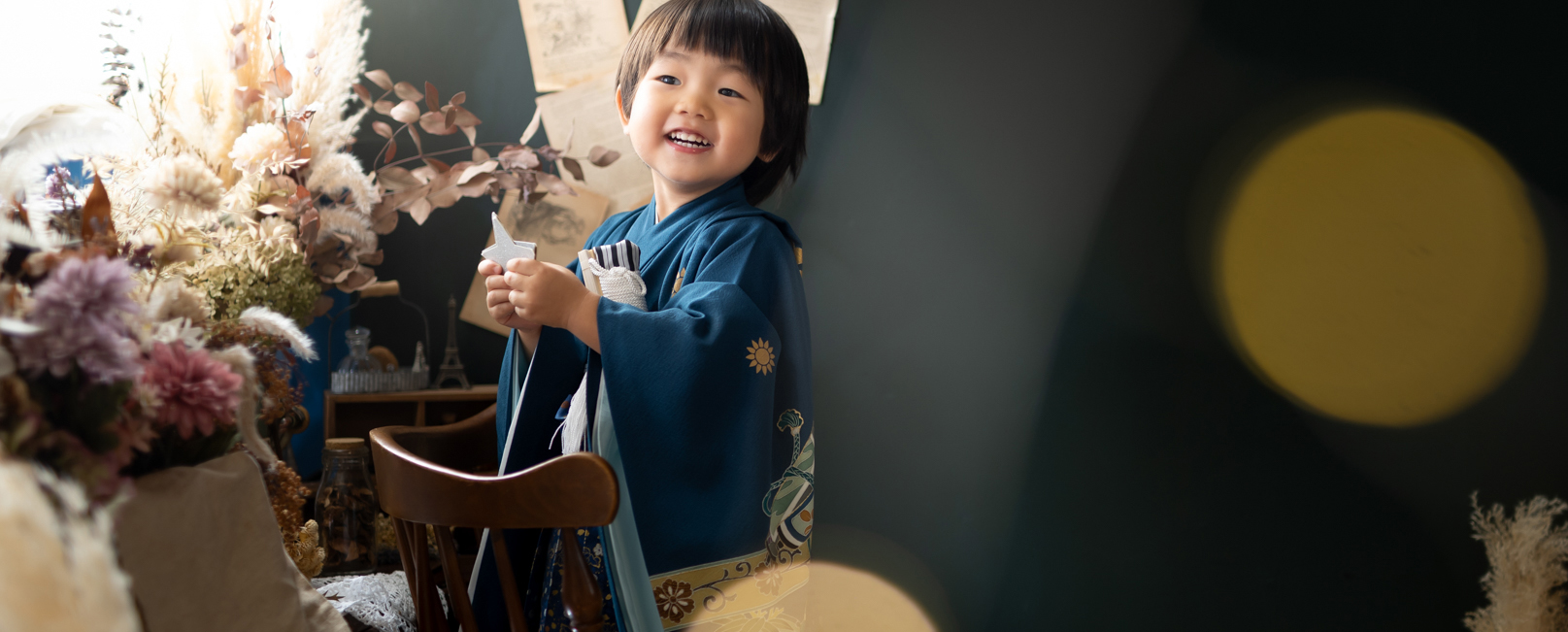 **代替テキスト:**
Photostudio PASSIONで、七五三の着物姿の3歳男の子が折り紙を手に、楽しそうな笑顔を見せるスタジオ写真。