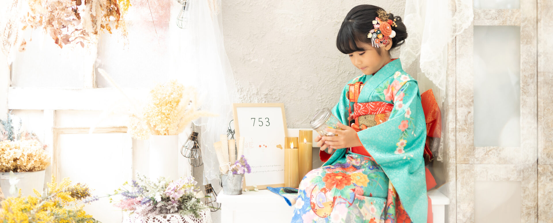 大分市のPhotostudio PASSIONで七五三撮影。水色の着物を着た7歳の女の子が、やわらかな光に包まれたスタジオで小物を手にする自然な姿