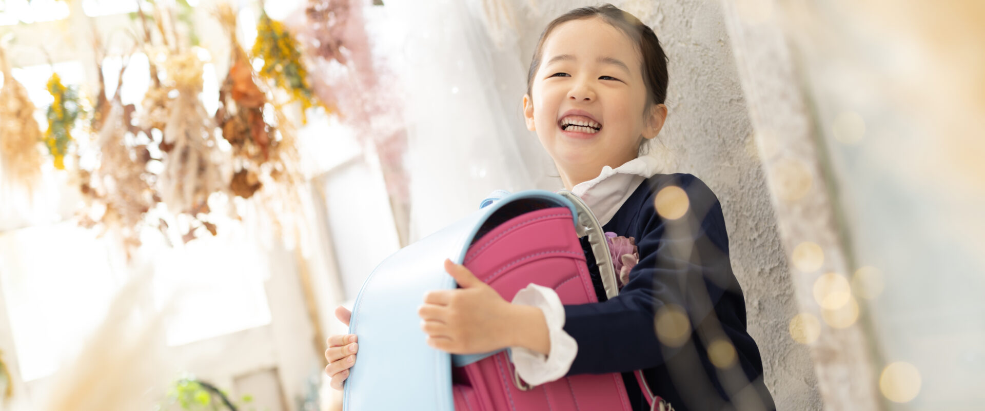 ピカピカのランドセルを背負い、ハレの日の喜びいっぱいにスタジオで微笑む可愛いお子さんの入学記念写真