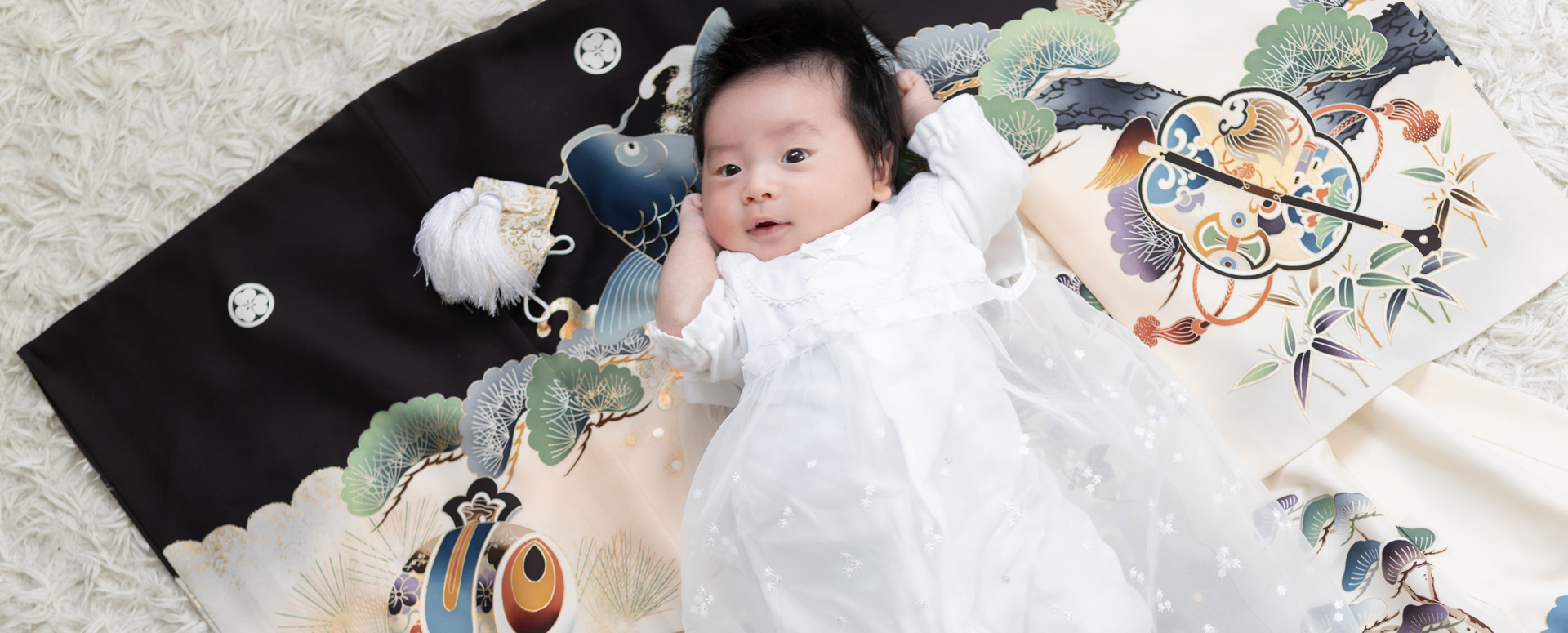 **代替テキスト:**
Photostudio PASSIONで、お宮参りの祝い着の上に寝転ぶ赤ちゃんを撮影した記念写真。