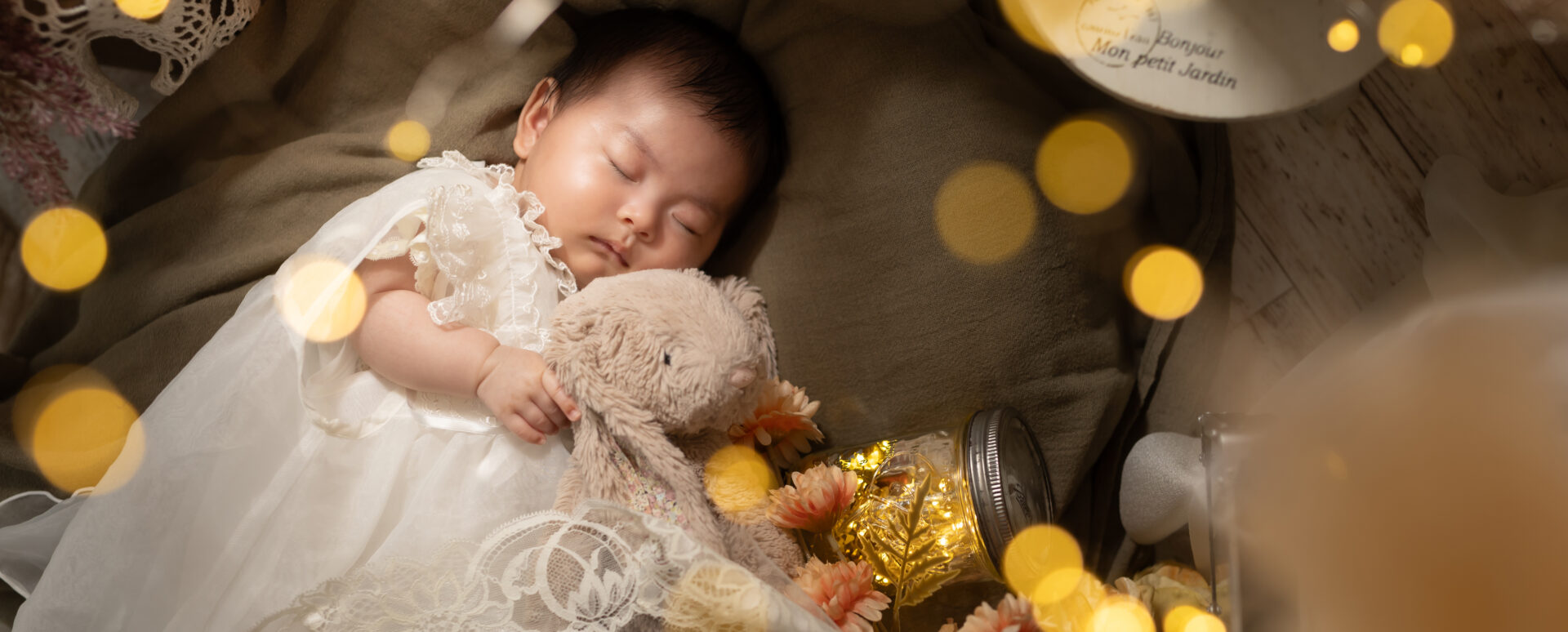 **代替テキスト:**
Photostudio PASSIONで、うさぎのぬいぐるみを抱きながら気持ちよさそうに眠る赤ちゃんを撮影したお宮参りの記念写真。
