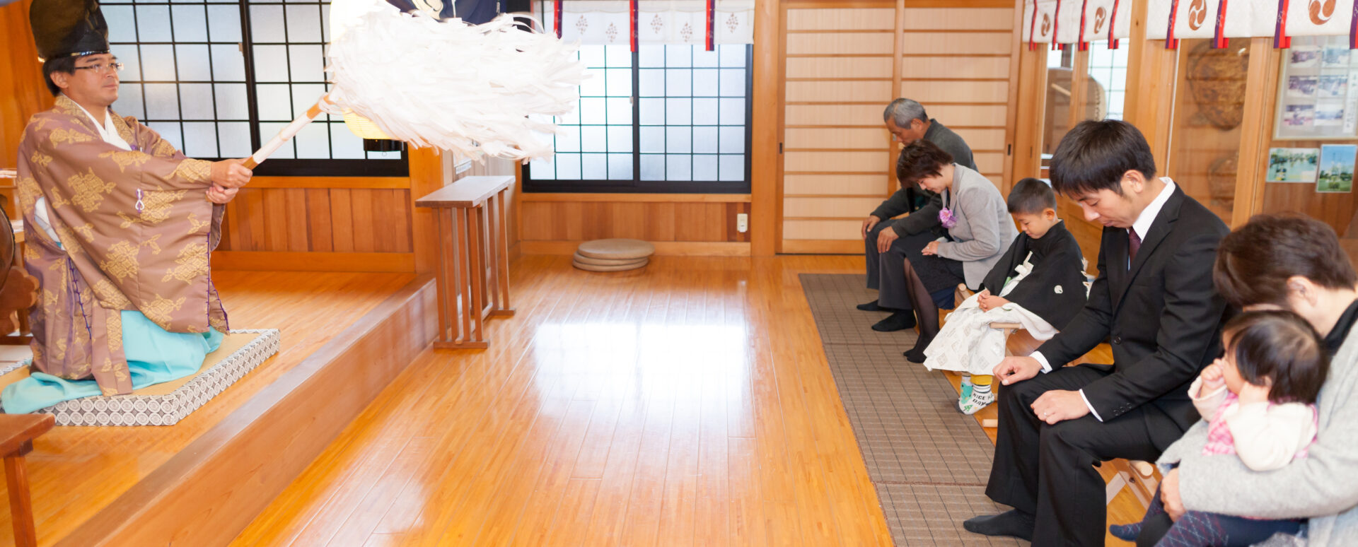 別府市の八幡竈門神社で七五三のご祈願を受ける男の子と家族。神職によるお祓いを受けながら、家族みんなで成長を願う七五三のお参り風景。