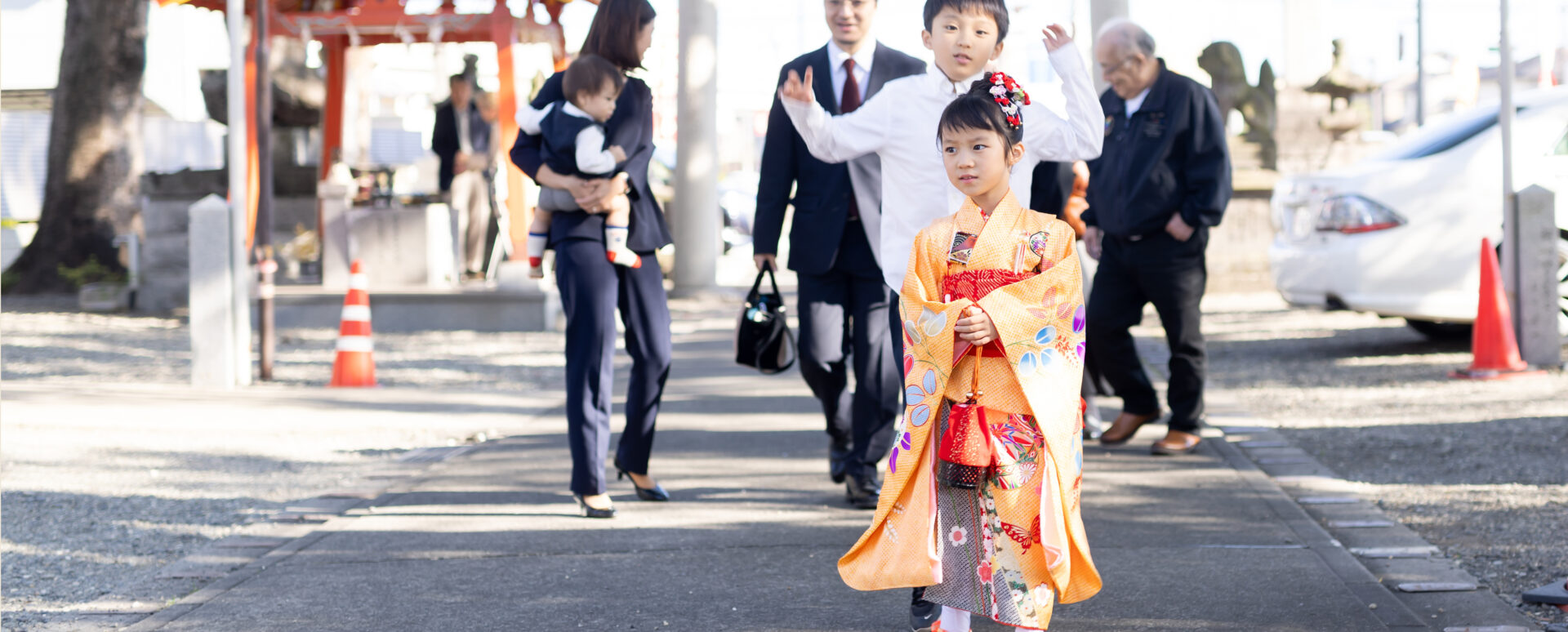 大分市の若宮八幡社で七五三のお参りをする女の子。参道を歩く姿を家族が温かく見守る自然な記念写真。