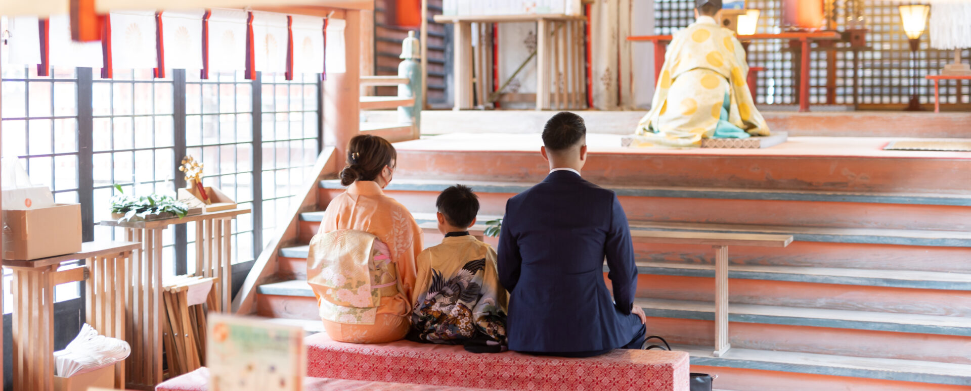 大分県大分市・柞原八幡宮で七五三のご祈願をする家族。着物姿の男の子を囲み、パパママと一緒に本殿へ向かって座る様子。