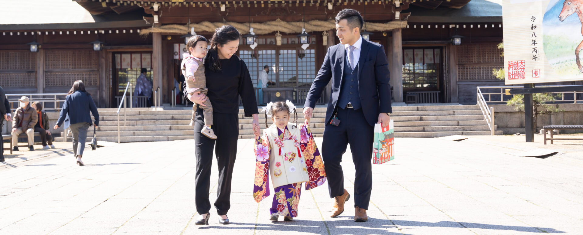 大分県大分市・大分縣護國神社での七五三。着物姿の女の子がパパママと手をつなぎ、きょうだいと一緒に境内を歩く家族の様子。