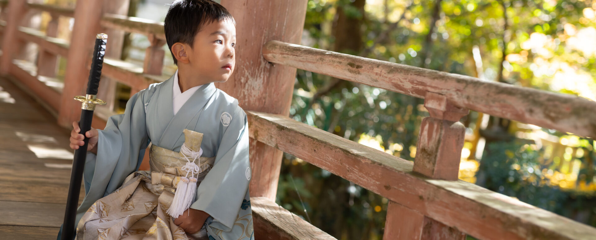 大分県大分市・柞原八幡宮での七五三。淡い水色の着物を着た男の子が刀を手に、境内の回廊にたたずむ姿。