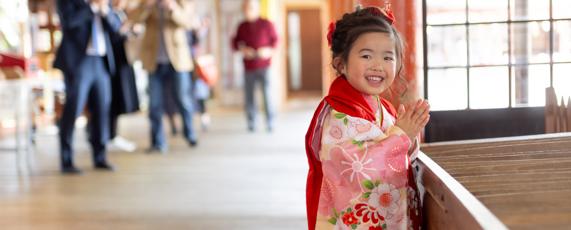 大分県大分市・柞原八幡宮での七五三。ピンクの着物を着た3歳の女の子が、笑顔で手を合わせてお参りする様子。