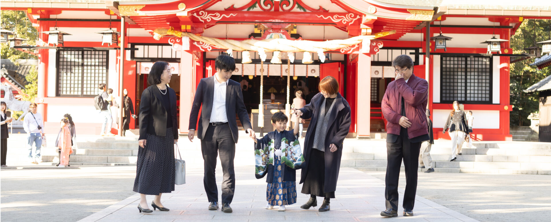 大分市の春日神社で家族と手をつないで歩く七五三の男の子。