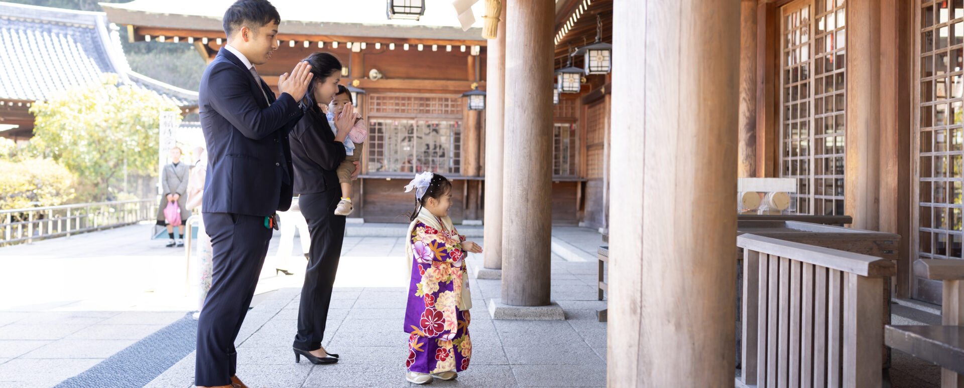 大分市の大分縣護國神社で七五三のお参りをする女の子。パパとママ、きょうだいと一緒に拝殿で手を合わせる家族の記念写真。