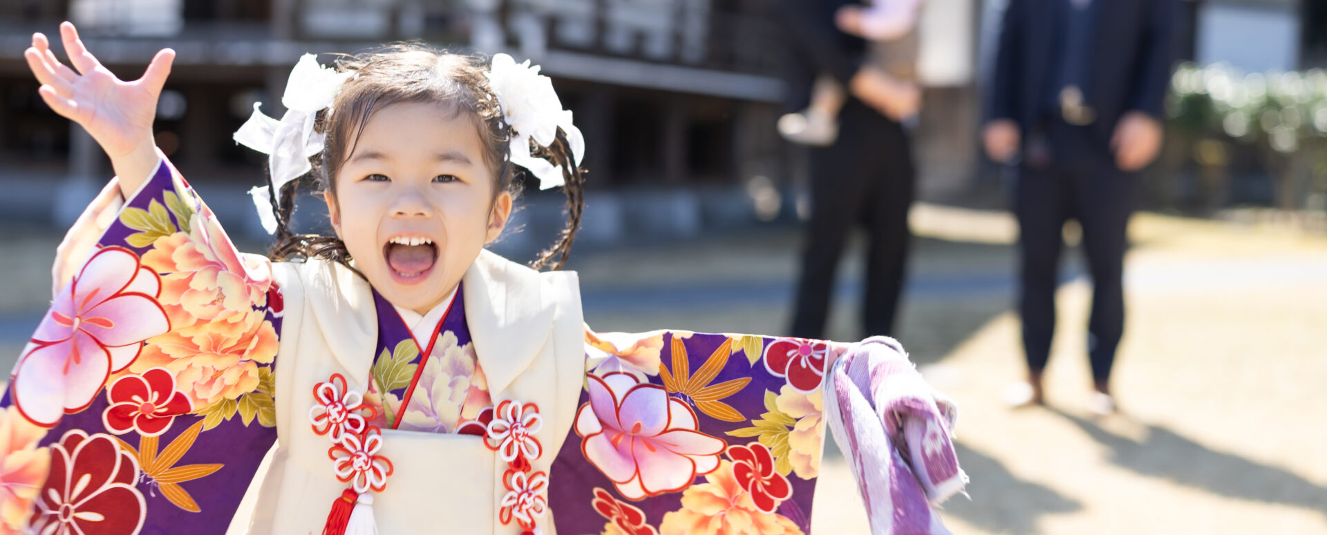 大分市の大分縣護國神社で七五三のお参りをする女の子。着物姿で元気いっぱいに手を広げ、楽しそうな笑顔を見せる記念写真。