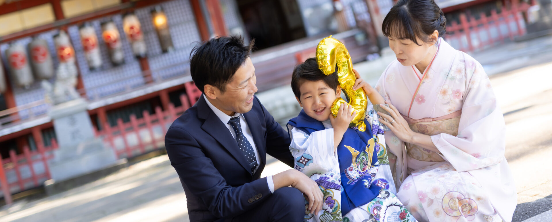 別府市の朝見神社で七五三のお参りをする3歳の男の子。数字のバルーンを抱え、パパと着物姿のママに囲まれて笑う家族の記念写真。