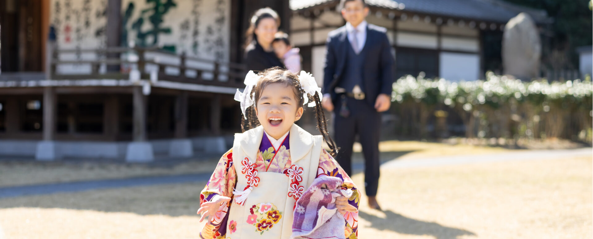 大分市の大分縣護國神社で七五三のお参りをする女の子。着物姿で元気いっぱいに走り、笑顔を見せる自然な記念写真。