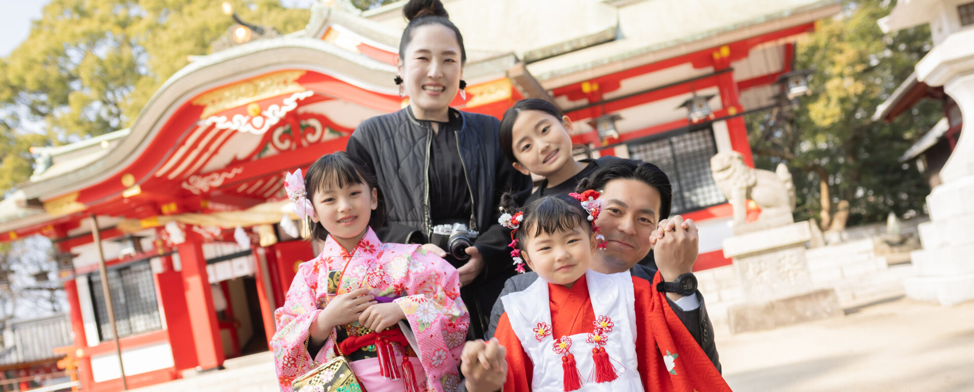 大分市の春日神社で七五三のお参りをする家族。本殿の雰囲気を背景に残した家族写真。