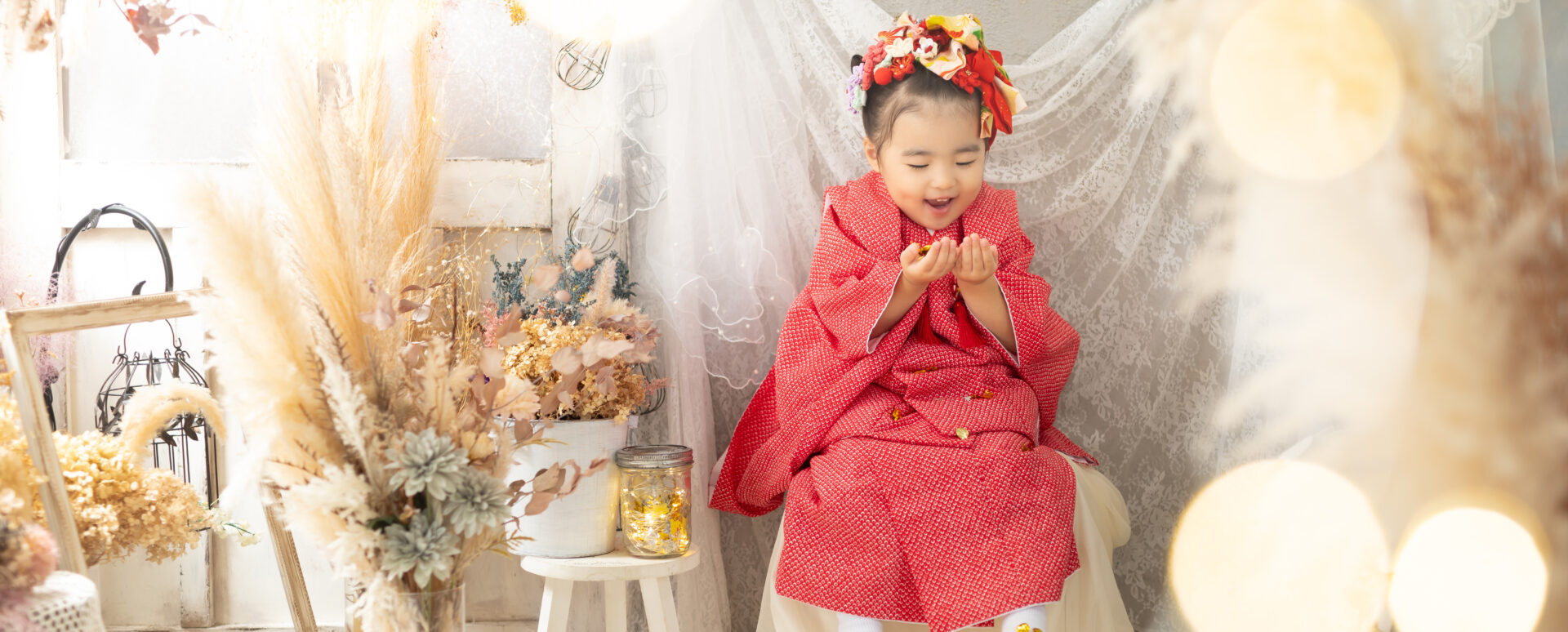 大分のPhotostudio PASSIONで、赤い被布姿で楽しそうな表情を見せる3歳七五三のスタジオ撮影