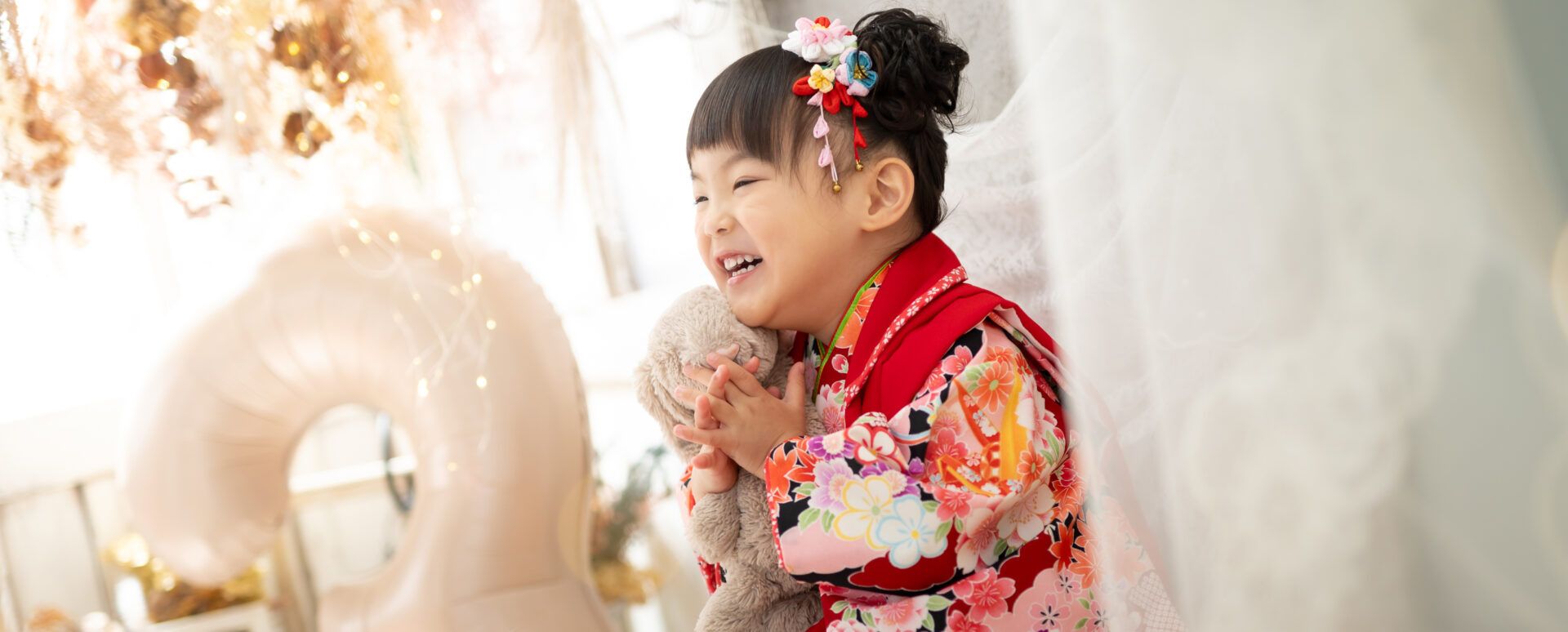 大分のPhotostudio PASSIONで、華やかな着物姿でぬいぐるみを抱きしめながら笑顔を見せる3歳七五三のスタジオ撮影