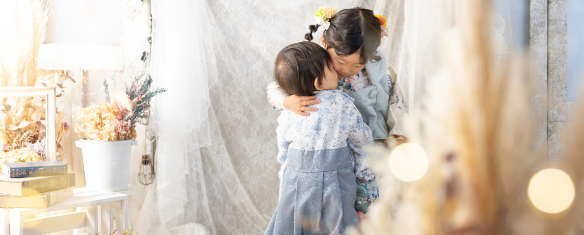 大分のPhotostudio PASSIONで、水色の着物姿の姉弟が優しく抱き合う七五三のきょうだい写真