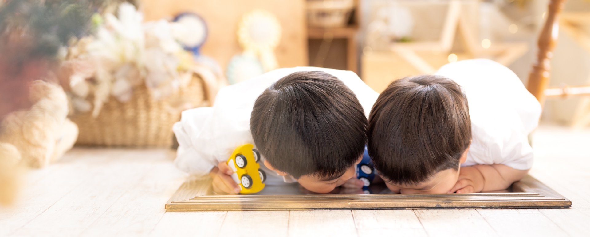 大分のPhotostudio PASSIONで、おもちゃの車で遊びながら仲良く寝転ぶ兄弟の自然なスタジオ撮影